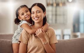 Parent smiling while holding a happy baby in a cozy room