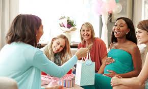 Baby shower guests sharing stories while the expectant mother opens gifts