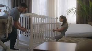 Parents setting up a baby crib as part of their nursery furniture