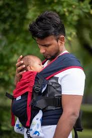 Father bonding with baby using a sling carrier