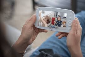 Parent holding a video baby monitor while watching on screen