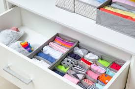 Stack of folded baby clothes on wooden dresser