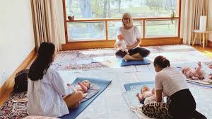 Parents learning baby massage techniques in a group setting.