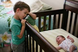 Older siblings bonding with new baby in crib
